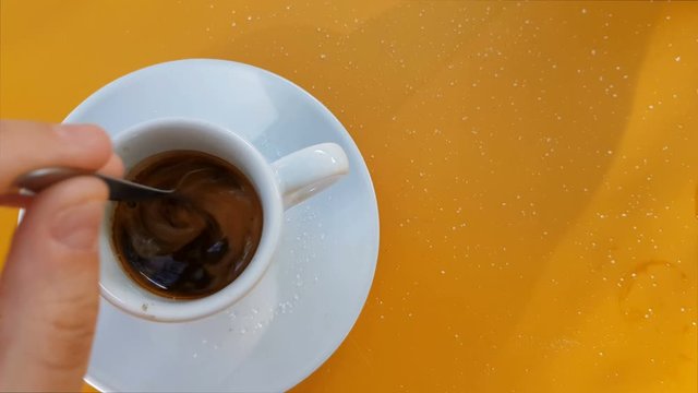 Top view of hand stirring sugar in coffee