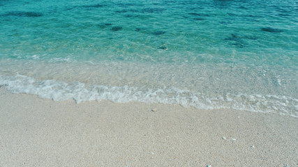 Beautiful background transparent surface wave, sand on clean seaside beach. Royalty high-quality free stock video footage of clean surface seawater, waves on the beach with sand and sunshine in summer