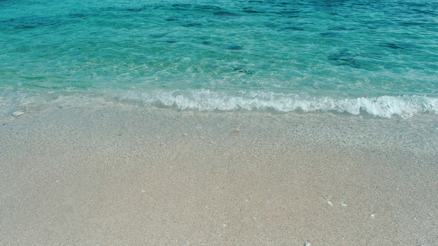 Emerald green water. Beautiful background transparent surface wave, sand on clean beach. Royalty high-quality free stock photo image of clean surface seawater, waves on the beach with sand in sunshine