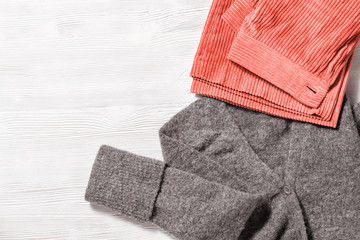 Trendy corduroy pants and warm wollen pullover on white wooden background. Female clothing trend color. Autumn comfortable clothes. Fashion concept. Flat lay. Top View.