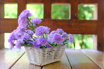 bouquet of flowers in a basket on wooden table