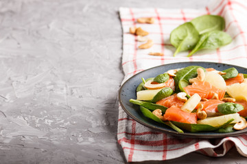 Fresh salmon with pineapple, spinach and cashew in blue ceramic plate on a gray concrete background.
