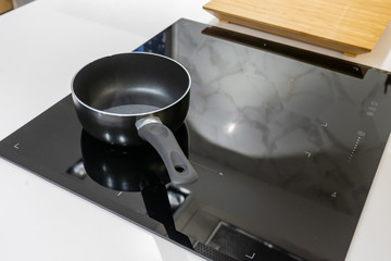Frying pan on modern black induction stove, cooker, hob or built in cooktop with ceramic top in...