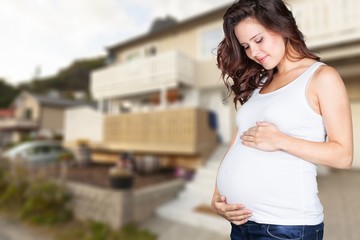 Pregnant young woman in white t shirt on bright background