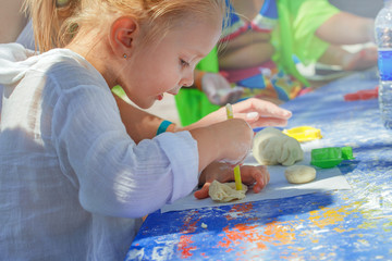 Little Girl Engaged In Modeling Plasticine in summer.