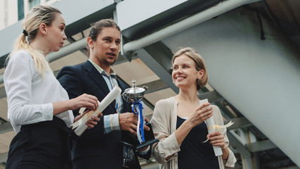 business background of business people in business wear are cheerful for being winner in business competition contest with hand holding trophy and award cerfiticate