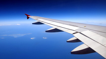 Fototapeta premium schöner Blick auf Flugzeugflügel zwischen tiefblauem Himmel und Meer mit kleinen Inseln