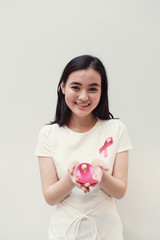 Asian young woman holding pink ribbon, breast cancer awareness, October pink concept