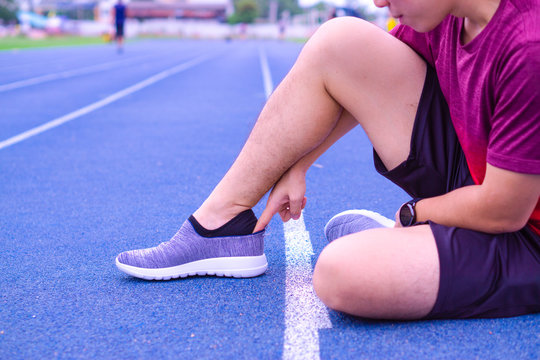 A man is taking on grey sports shoes on the running track. Sport and exercise concept. © saran