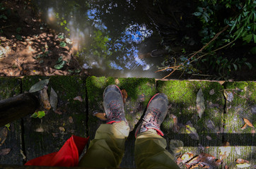 legs of men standing on bridge in rain forest