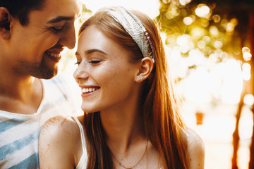 Outdoor shoot of a lovely young couple smiling. Beautiful red haired woman laughing while embracing with her boyfriend.