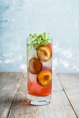 Cocktail with plums and thyme on the rustic background. Selective focus. Shallow depth of field.
