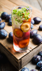 Cocktail with plums and thyme on the rustic background. Selective focus. Shallow depth of field.