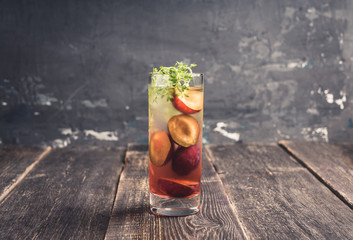 Cocktail with plums and thyme on the rustic background. Selective focus. Shallow depth of field.