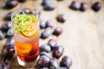 Cocktail with plums and thyme on the rustic background. Selective focus. Shallow depth of field.