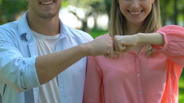 Cheerful boyfriend and girlfriend making fists-bump, trustful relationships