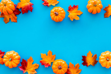 Autumn background with leaves and pumpkins on blue top view space for text frame