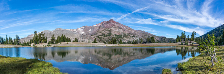 Volcanic mountain in morning light reflected in calm waters of lake.	