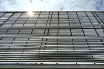 Angle view of steel fence against the sky and sun rays