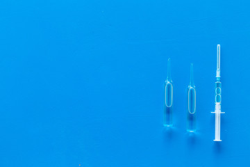 Flu vaccination. Ampoule and syringe on blue background top view copy space