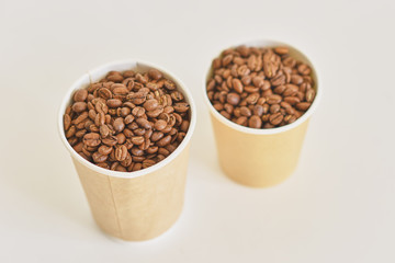 Two paper coffee cups with coffee beans on white background