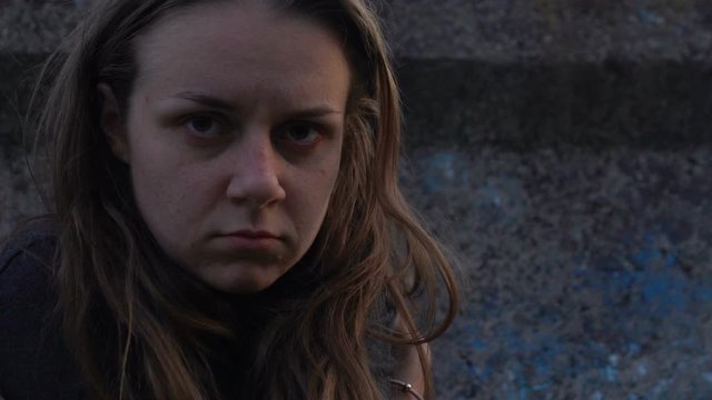 Homeless young woman in abandoned lane suffering from drug addiction, poverty
