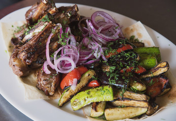 rack of lamb with grilled vegetables, decorated with sweet onion sweet onion on a white platter