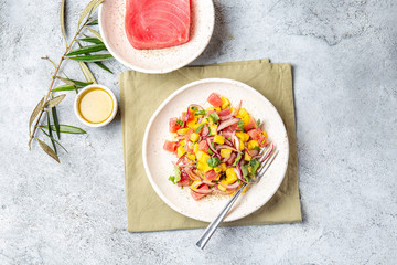 Gourmet tuna mango salad tartar with cilantro and purple onion on white plate