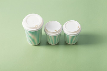 Fototapeta na wymiar disposable paper cup with coffee on green background