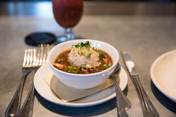 a close up of a bowl of cajun gumbo on the table ready for customers