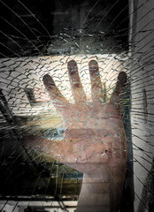 The man is on the street, behind the broken glass. The man presses his hand to the glass.