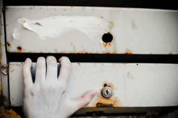 Mailboxes hang on the wall of the house. A woman's hand lies on the surface of the mailbox.