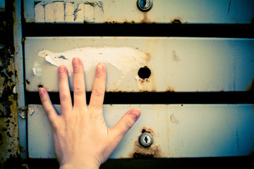 Mailboxes hang on the wall of the house. A woman's hand lies on the surface of the mailbox.