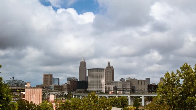 Cleveland, Ohio time-lapse of the downtown skyline with dramatic clouds passing by. Subway train passes on the rapid track in the foreground with the terminal tower as a backdrop.