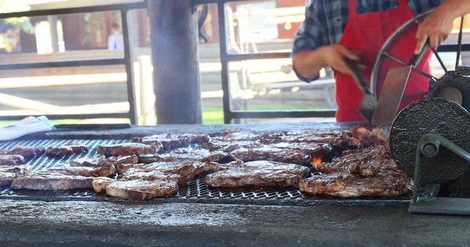 BBQ cooking steaks meat ona  grill. Outdoor family gathering and picnic. Hamburgers, steak and chicken cooked over fire. Outdoor recreation and meal time for lunch or dinner.