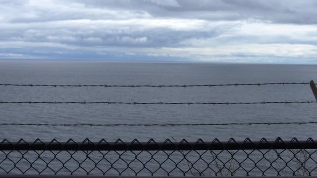 Barbed wire fence and lake with no horizon in cloudy dark weather