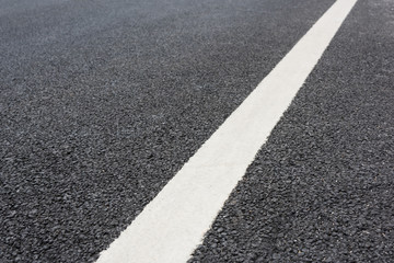 Fototapeta premium A white paint on a clean and tidy black asphalt road slash low angle close-up space background