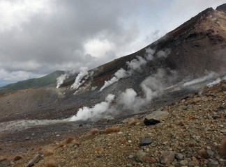 The highest peak in Hokkaido, Japan —Asahidake volcano mountain with white smoke coming out of the ground on a cloudy September afternoon