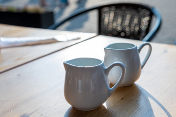 Two white cups of coffee on a table of outdoor cafe.