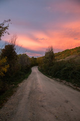 A mountain road below orange and yellow coloured clouds at sunset