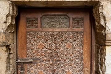 Geometrical engraved decorations of an aged wooden ornate door of Abd El Latif El Korafi historic mosque, signed by the maker, Gamalia district, Old Cairo, Egypt