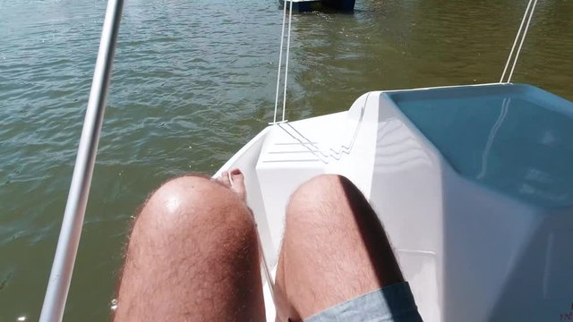 POV male hairy feet kicking paddleboat on lake