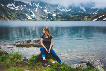 Young woman sit near Beautiful lake in Tatra mountains. Poland - obrazy, fototapety, plakaty