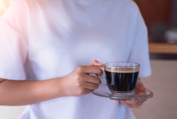 Naklejka premium Close up of woman hand holding coffee cup in cafe.