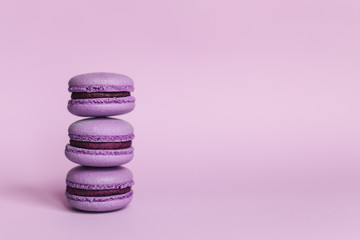Three purple french macarons on a purple background. Place for text.