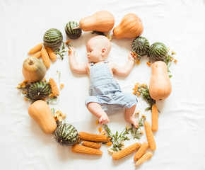 Cute baby lies in a circle of autumn harvest