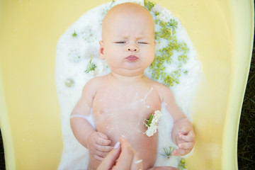 Close up of a baby in milk bath with natural flowers
