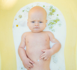 Close up of a baby in milk bath with natural flowers
