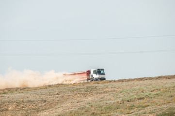 truck driving on sandy road picking up dust