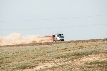 truck driving on sandy road picking up dust